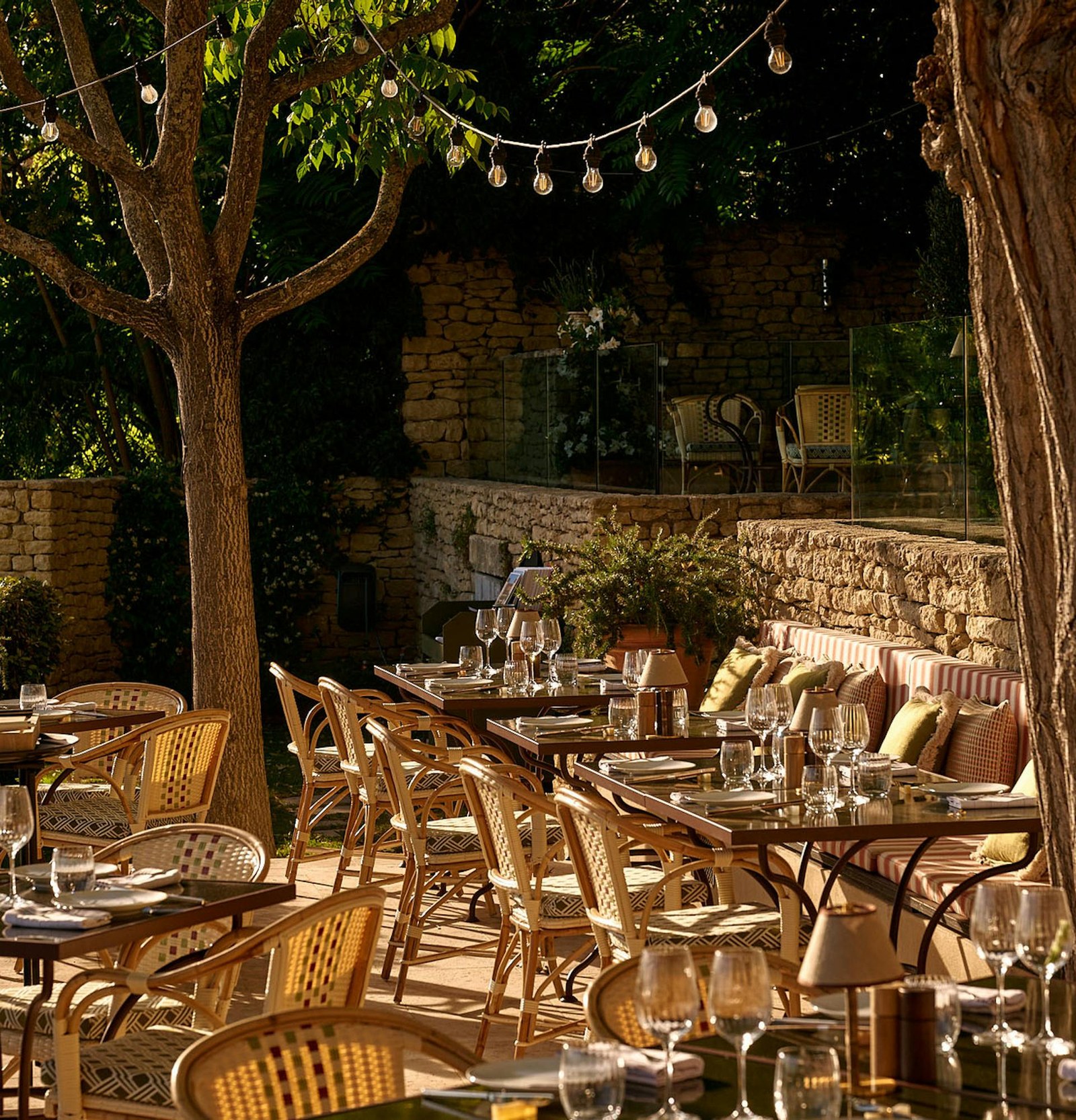 Tables dressed under the trees and festoon lights against the dry stone walls