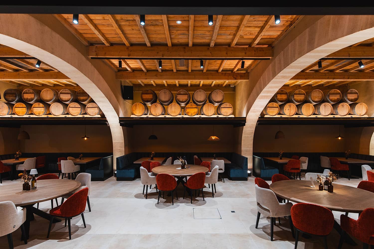 The vaulted hall of the Grand Chai, round tables under the barrel racks