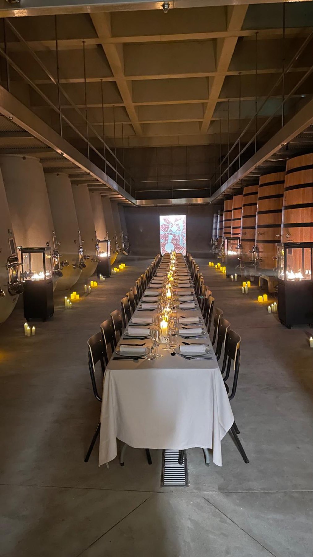 Long table set for dinner among the chai's barrels and tanks at Domaine Les Davids